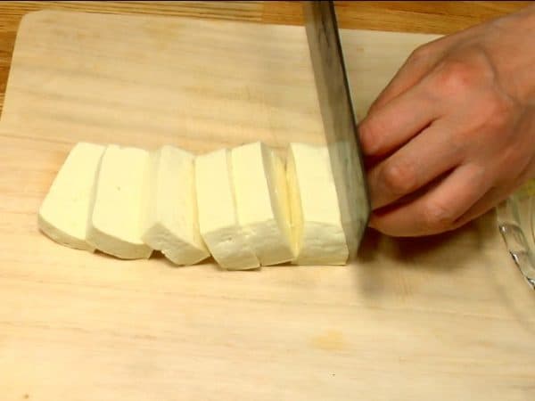 Remove the paper and slice the firm tofu into 1 cm (0.4") slices.