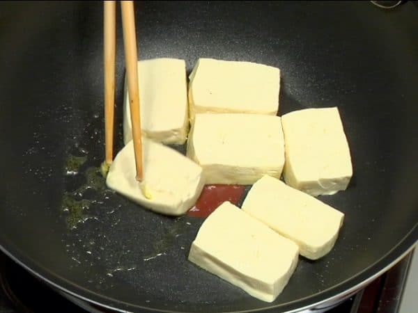 Grease the saucepan again. Add the sliced firm tofu and brown the surface.