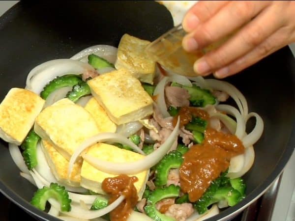 Add the sliced firm tofu. Pour in the mixed condiments and keep mixing the ingredients.