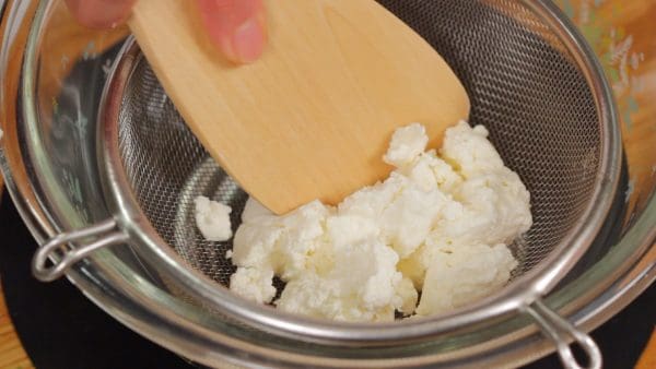 First, press the fresh cheese through a mesh strainer to help create a smooth texture.
