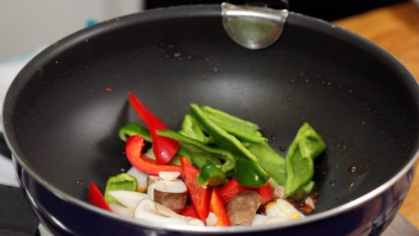 When the aroma grows stronger, add the long green onion, bell peppers, and shiitake mushroom.