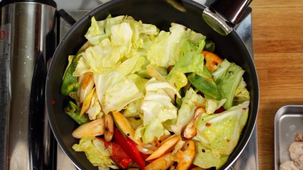 When the bell pepper begins to soften, add the spring cabbage leaves. Continue to stir-fry.