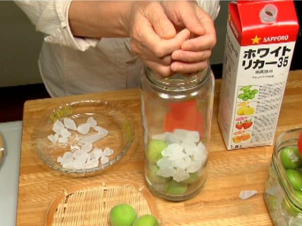 Let's make umeshu. Add the green ume in the sterilized container. Add the rock sugar.
