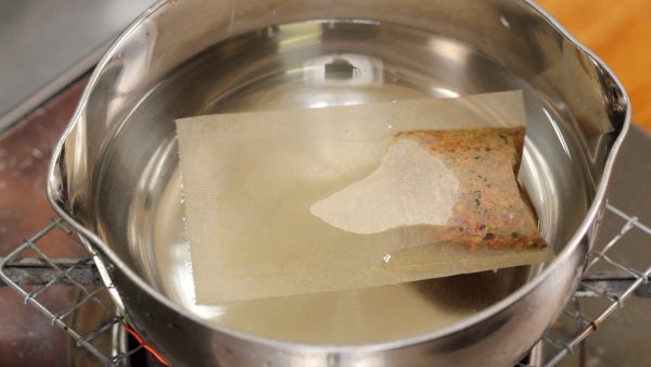 First, soak the dashi pack in the pot of water, and turn on the burner. This dashi pack contains coarsely ground real bonito flakes and kombu seaweed, and it will allow you to make authentic dashi stock quickly.
