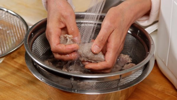 Remove the gyusuji with a mesh strainer and place it into a bowl of water. Carefully rinse the meat under running water.