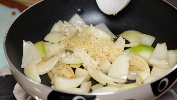 When the onion is lightly browned, add the chopped garlic and ginger root. Continue stir-frying until aromatic.