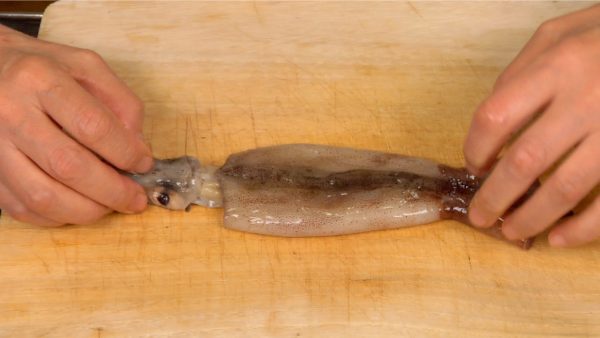 Let’s clean the squids. First, detach the mantle collar from the head. Hold the lower part of the eyes and gently pull on the fins.