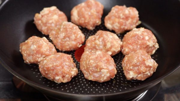 Now, let’s make the meatballs. Add the vegetable oil to a pan and turn on the burner. Coat your hands with oil, shape each piece into a ball and quickly place it into the pan.