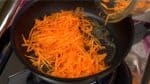 Để cà rốt thái sợi vào chảo và xào bằng đũa nhà bếp.