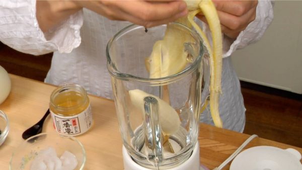 Let's make the Healthy Black Sesame Smoothie. Peel the banana, divide it in half and place it into the blender.