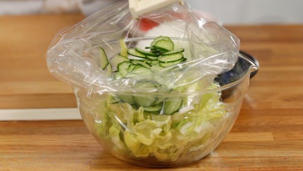 Place the cabbage into a clean plastic bag. Next, with a mandoline slicer, thinly slice the cucumber.