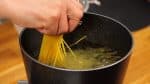 Now, let's cook the pasta. Add the 0.7 to 1 percent salt to the pot of hot water, and bring it to a boil. When you use a small pot, gradually submerge the spaghetti in the water as it softens.