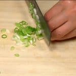 Let's prepare the fillings. Chop the spring onion leaves into fine pieces.