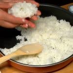 Eine Portion Reis in die Handfläche legen und in der Mitte ein kleines Loch eindrücken.