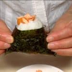 Make a shallow hole in the top corner of the onigiri and fill with the salmon.