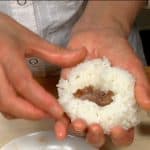 Die Querrippen-Onigiri werden auf die gleiche Weise zusammengesetzt: Eine Portion Reis mit Fleischstücken füllen und zu einem Dreieck formen.