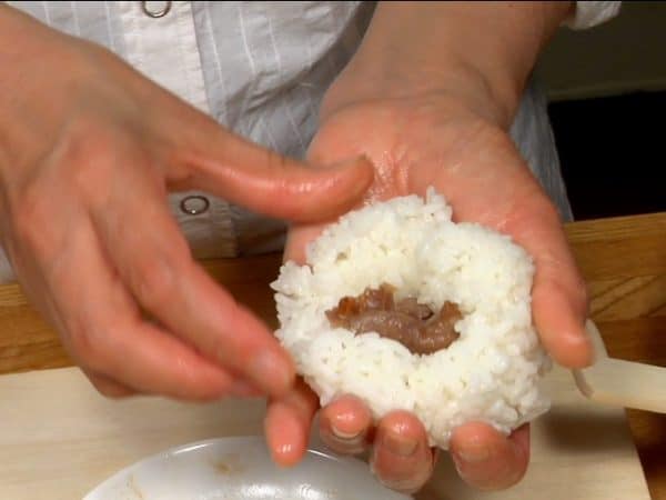 Repeat the process to make the short rib onigiri. Place part of the short ribs onto the rice and shape the onigiri into a triangle.