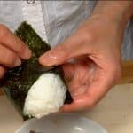 Bọc cơm nắm onigiri bằng rong biển nori hình tam giác.