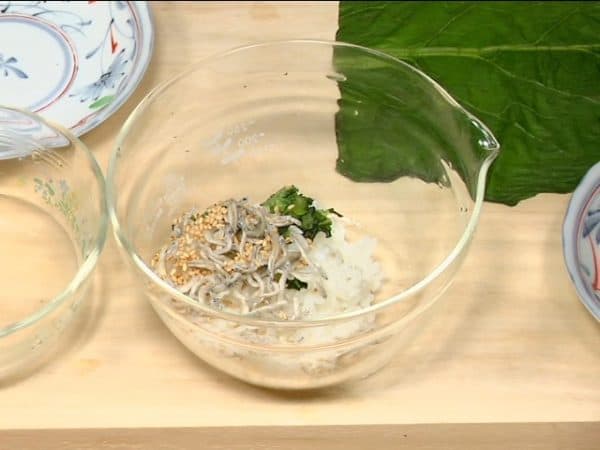 Let's make a hiroshimana onigiri. Combine the rice, stem of pickled hiroshimana, chirimenjako, dried baby sardines, and toasted white sesame seeds.