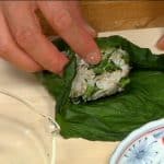 Enrolla el onigiri con la hoja de hiroshimana encurtida. 