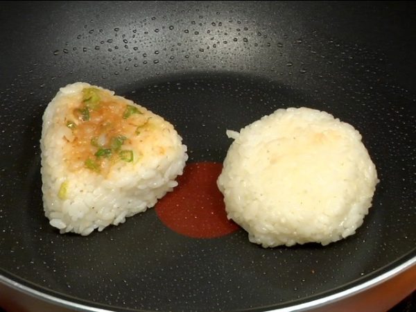 Now we can grill them and make yaki onigiri! Coat a heated pan with the sesame oil. Place the negi miso and soy sauce onigiri into the pan.