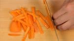 Như củ cải daikon, cắt cà rốt thành các lát, chồng chúng lên nhau và thái sợi chúng thành các dải.