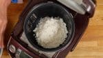 Primeiro, enxágue a quantidade de arroz equivalente à um copo de medir, seque bem e coloque em uma panela de arroz.