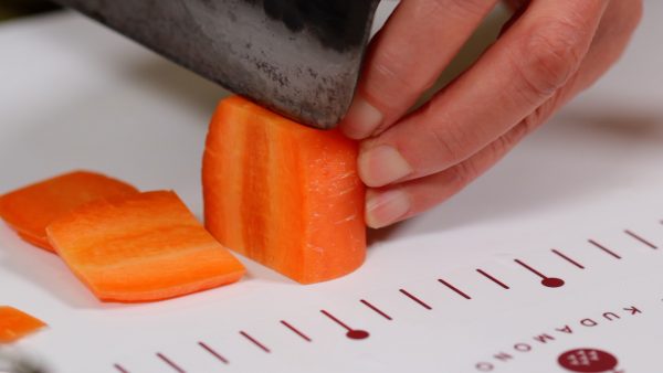 And now, let’s cut the vegetables. Cut about a 3cm (1.2") thick piece of the carrot. Slice it into 5mm (0.2") slices and chop it into fine strips.