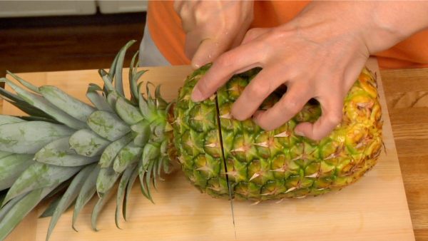 Let’s prepare the pineapple for the ice cream. First, cut off the top of the pineapple, removing the crown.