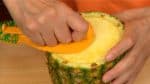 Place the pointed nail into the core, adjust the outer blade to the skin and press the cutter into the pineapple. Turn the cutter clockwise and make a shallow circular cut.