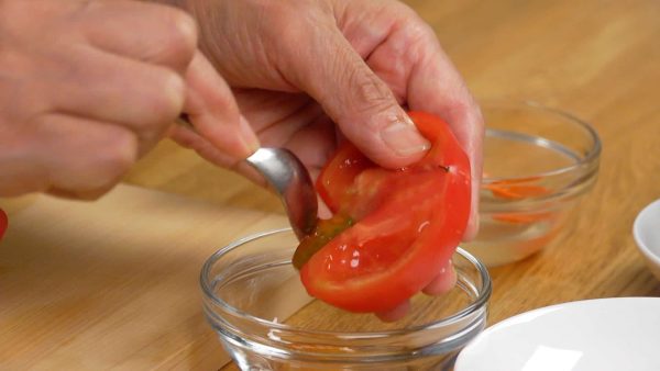 Remova o cabinho do tomate e corte-o em fatias de 1cm. Retire as sementes para que a cor vermelha do tomate se destaque no prato. Reserve as sementes em uma tigela.