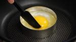 Then, place the egg into the egg ring. With a spatula, keep the yolk in the center until the white begins to firm up. Sprinkle on the salt and the pepper.