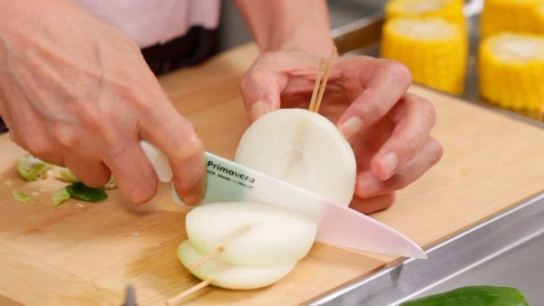 Next, pierce the onion with bamboo sticks until they reach the core as shown. Then, cut the onion between the sticks, slicing it into 1 cm (0.4") slices.