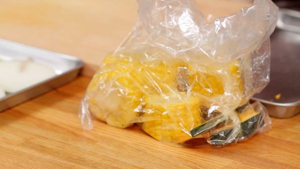 Place the sliced pumpkin and boiled corn on the cob into a plastic bag and add the olive oil. And toss to coat evenly.