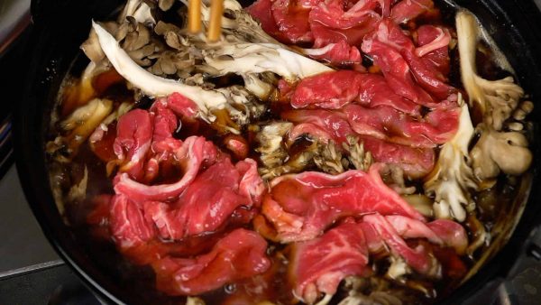 When it begins to boil again, add the maitake mushrooms, beef slices and the long green onion.