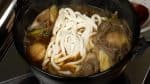 Quand vous avez fini la plupart des ingrédients initiaux, vous pouvez ajouter des nouilles udon et de la ciboulette pour finir le reste de bouillon.