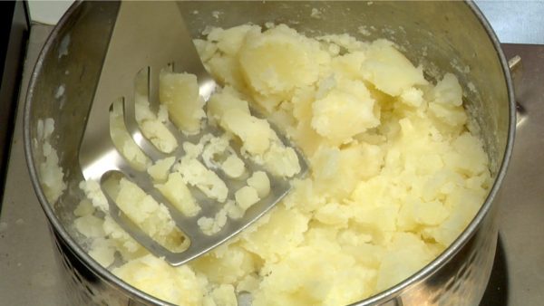 Turn off the burner and mash the potatoes while they are still hot.