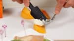 Spoon the cream cheese onto the persimmon wedge.