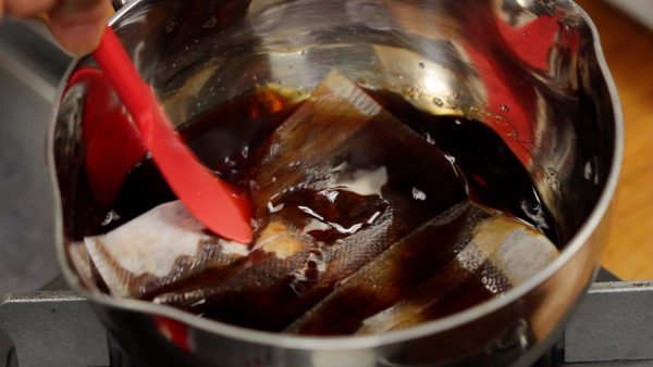 When you don't smell any alcohol, add the soy sauce and the bag of bonito flakes. Submerge the bag in the sauce completely.