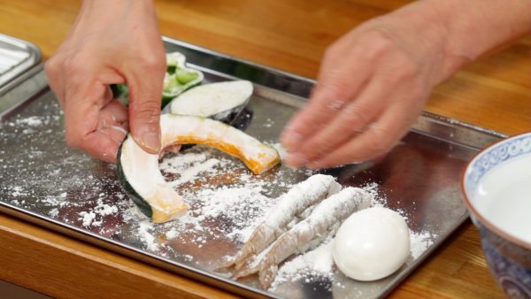 Place all the ingredients on a tray and dust them with tempura batter mix. Remove the excess powder and coat both sides evenly. This process will help keep the batter from falling off. Avoid dusting too much otherwise the batter will become dense and heavy when deep-fried.