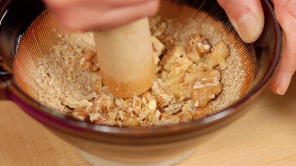 Then, add the walnuts. Crush them with the surikogi pestle.