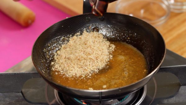 Now, heat the pan and continue stirring the mixture. When the sugar is dissolved, add the ground walnuts and sesame seeds.