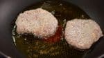 Maintenant, préparez le tonkatsu, porc pané frit. Faites chauffer une quantité généreuse d'huile dans une poêle et faites frire le porc pané sur feu moyen. 