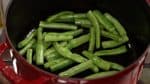 Now, let’s make the chicken curry. Turn on the burner and add vegetable oil to a pot. Suate the string bean pods on medium heat. Green bell peppers, okra and snap peas can also be used.