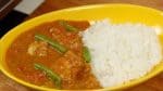 Ladle the delicious yogurt chicken curry next to the rice in a bowl.