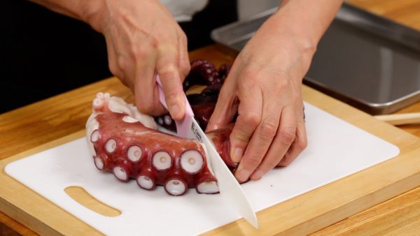 Now, the octopus has cooled. Let's slice it for sashimi. Cut the arm in half.