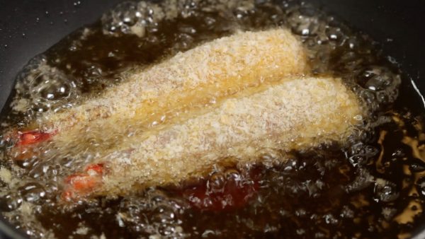 Now, heat the frying oil to 170~175 °C (338~347 °F) in a pot. Then, gently place the prawns into it. When the temperature is right, small bubbles should form around the breadcrumbs.