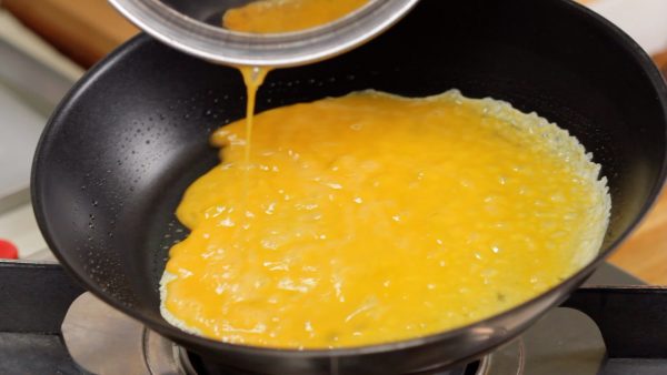 Coat a pan with vegetable oil. Drop in a bit of egg to check if the pan is hot. Then, pour the beaten egg into the heated pan and quickly distribute it.