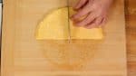 Place the egg onto a cutting board. Cut the egg sheet into 4 quarter moons.