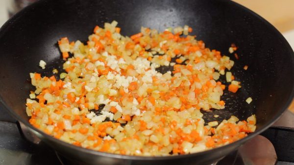 When the vegetables slightly brown and the aroma grows stronger, reduce the heat to low. And then, add the chopped garlic clove.